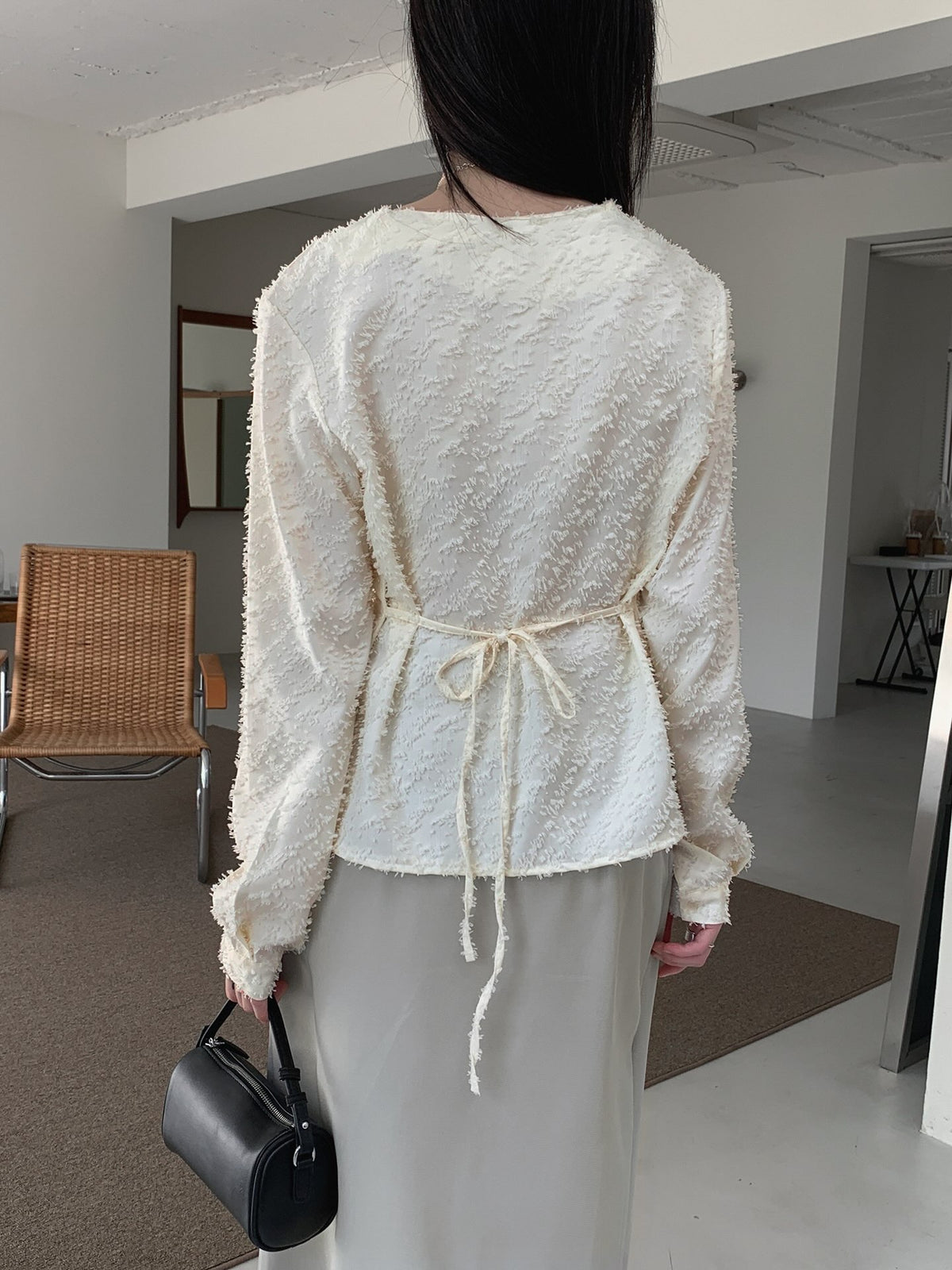 Front mirror view of a cream textured blouse with a draped cowl neckline and long sleeves.