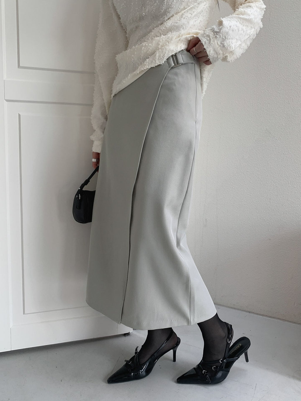 Close-up of the rectangular buckle and overlapping waistband on a charcoal skirt.