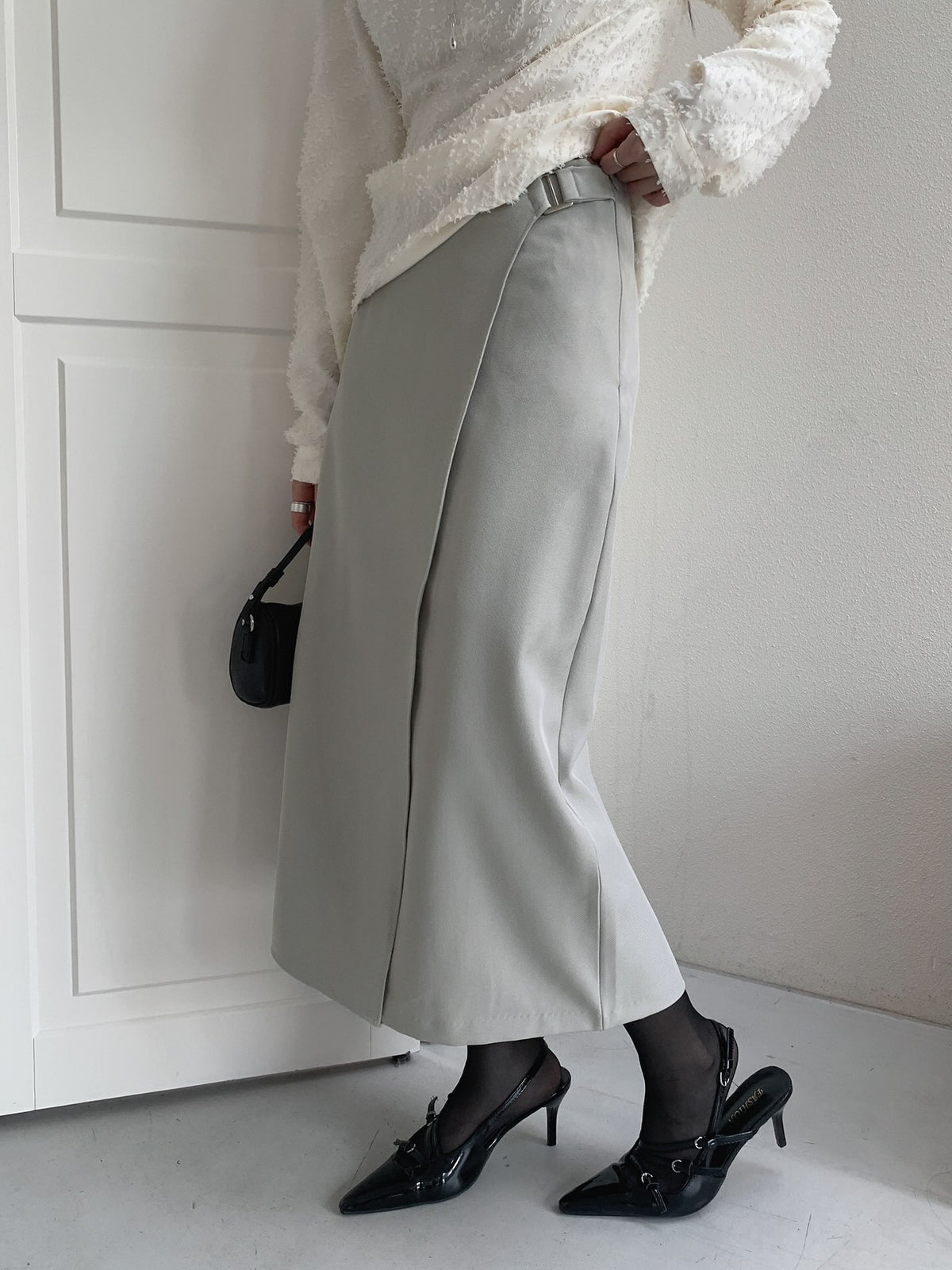 Close-up of the rectangular buckle and overlapping waistband on a charcoal skirt.