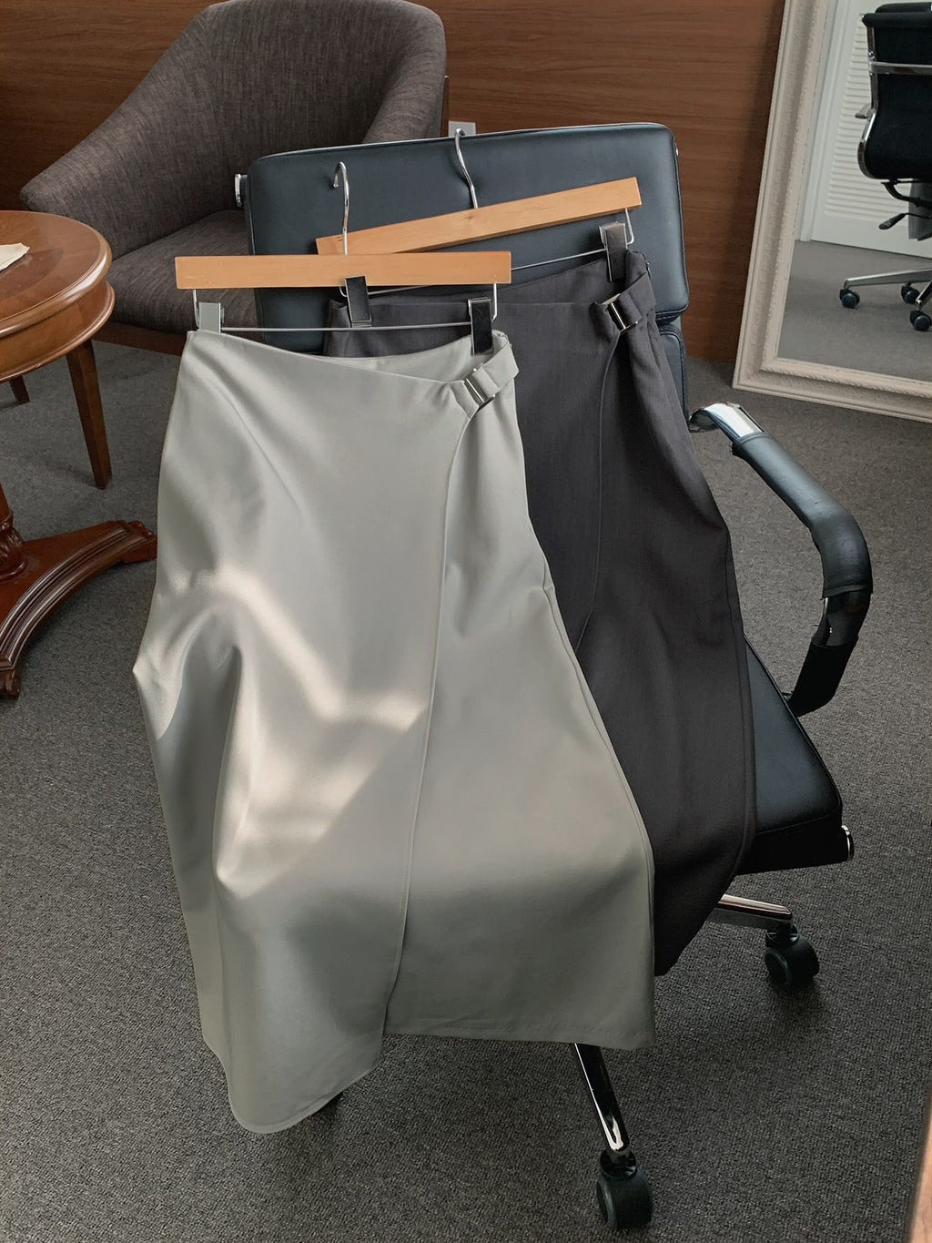 Beige and charcoal Rowsatnd midi skirts on hangers showing rectangular waist buckles.