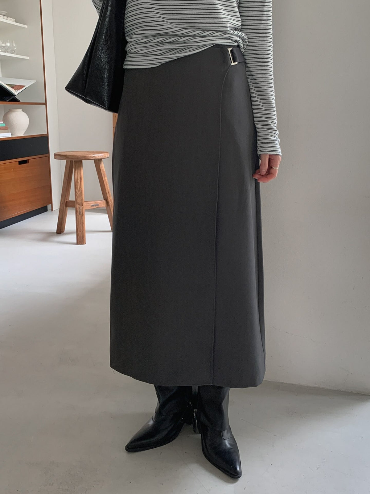 Front view of a charcoal wrap-style midi skirt with a striped top and black boots.