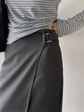 Full-length mirror view of a charcoal midi skirt styled with a striped top and black boots.
