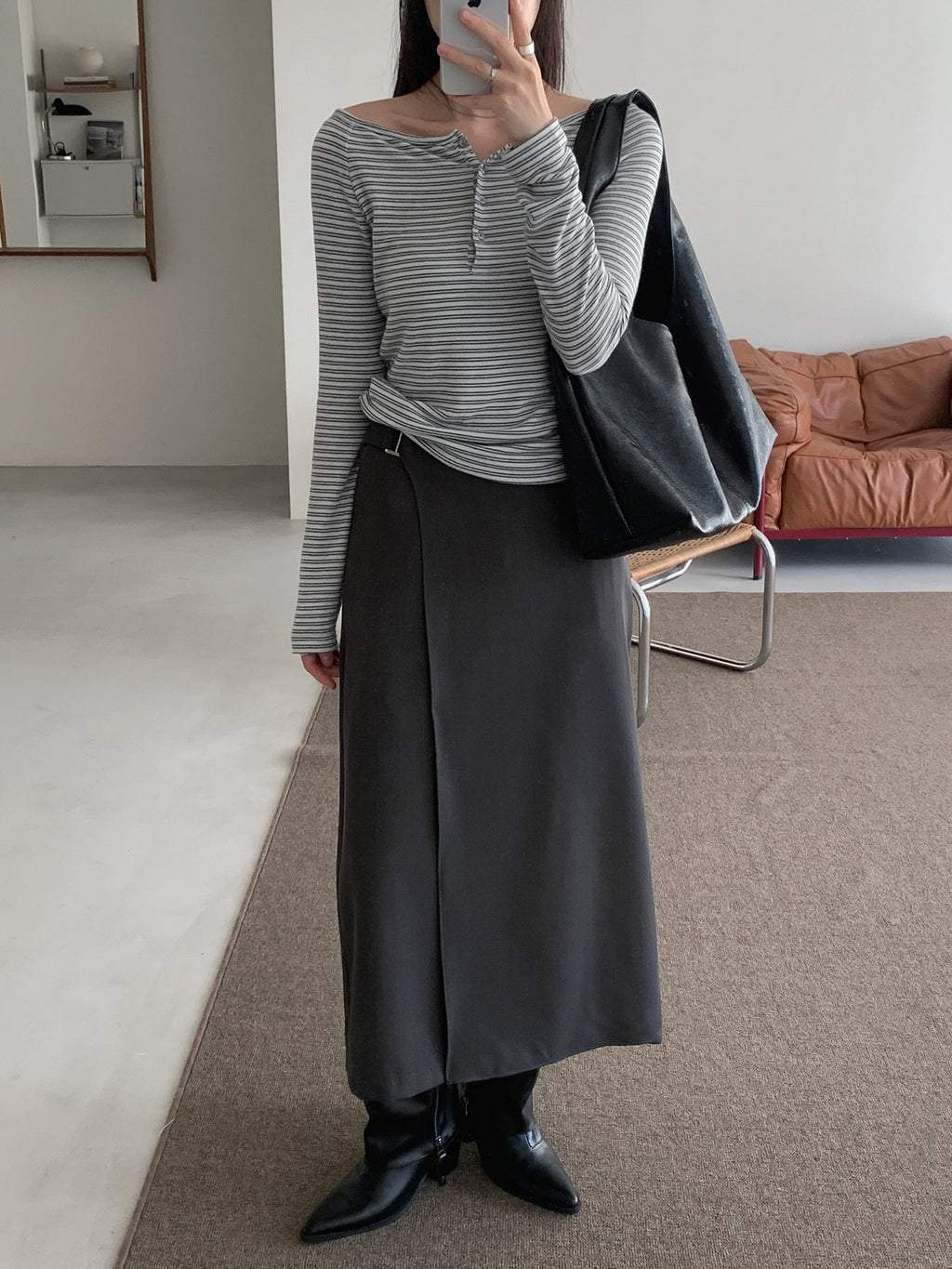Beige midi skirt showing the overlapping front panel and rectangular waist buckle.