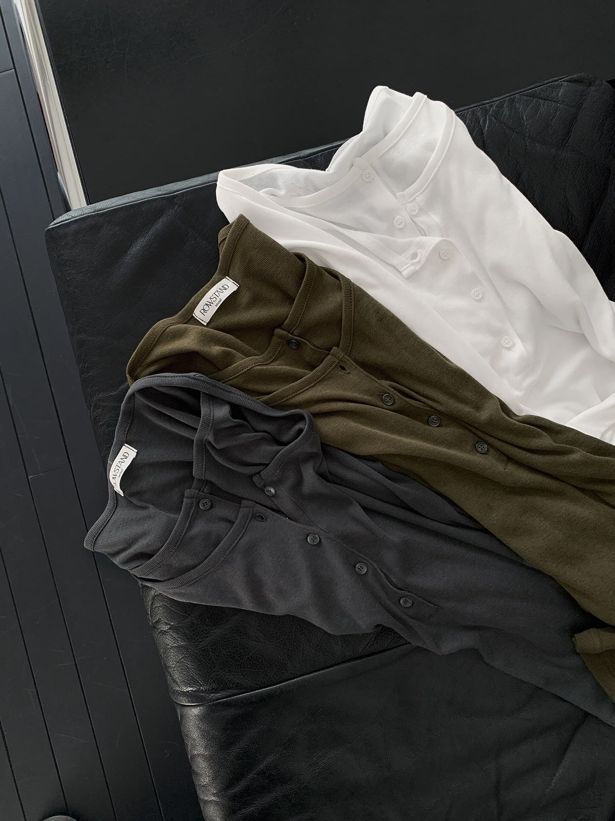 Front close-up of a charcoal top showing the layered neckline, button placket and long sleeves.