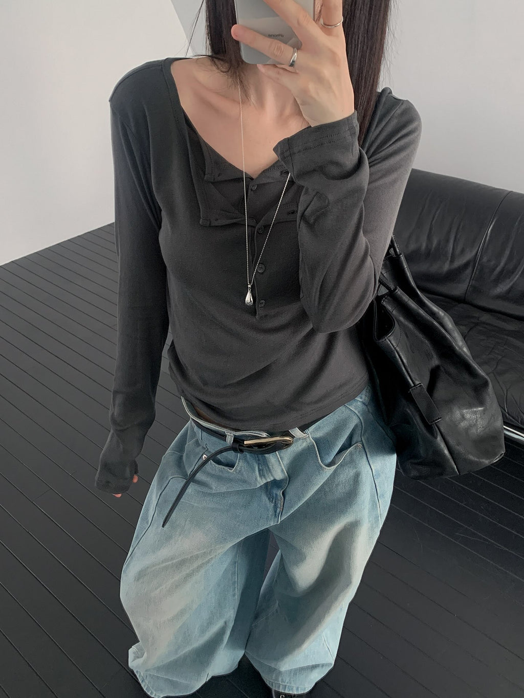 Rowsatnd button-detail tops in Charcoal, Khaki and White laid on a black sofa.