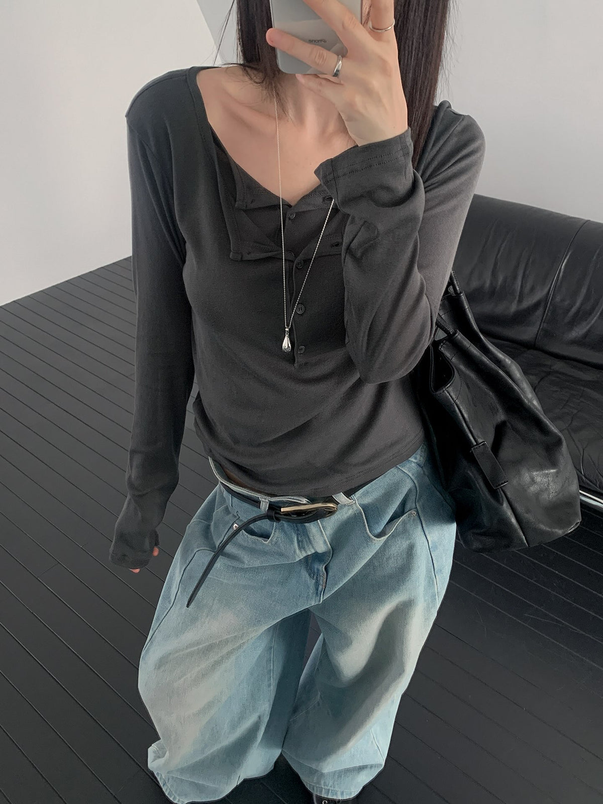 Rowsatnd button-detail tops in Charcoal, Khaki and White laid on a black sofa.
