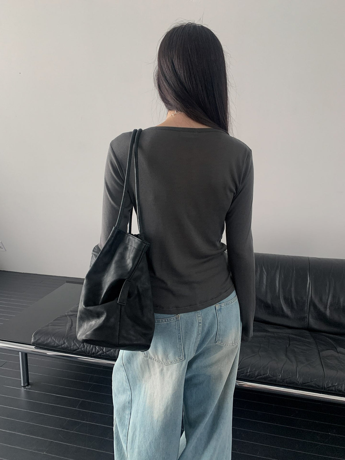Back view of a charcoal long sleeve top worn with light blue jeans.