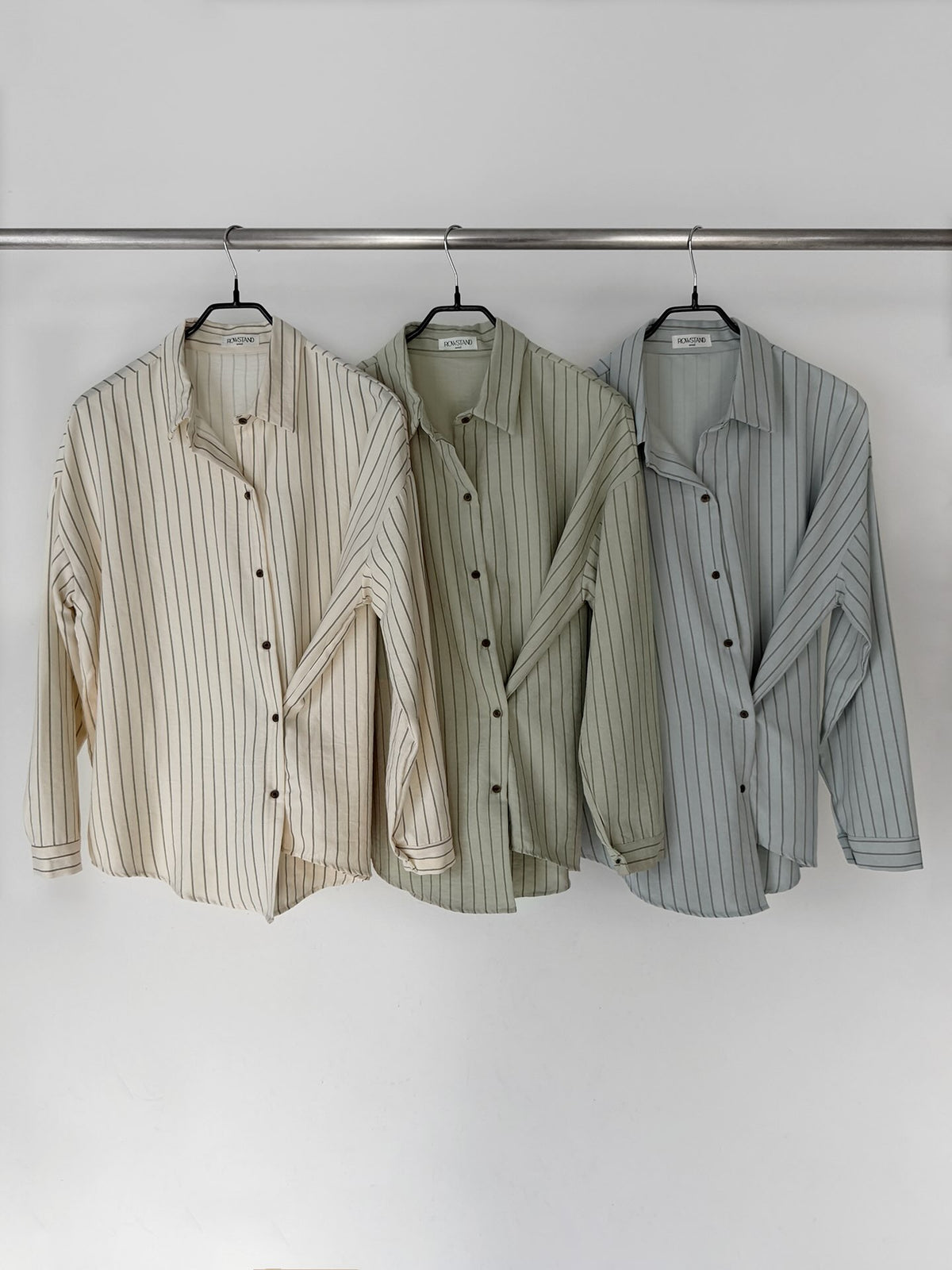Mirror view of a sky blue striped long sleeve shirt with a curved hem.
