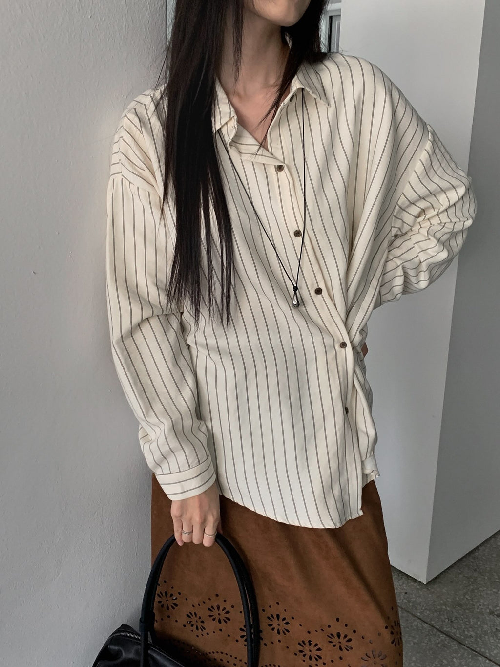 Front detail of a sky blue striped shirt with a pointed collar and dark buttons.