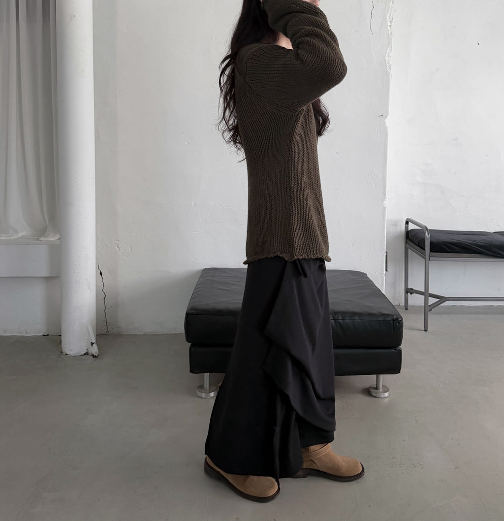 Full-length side view of a charcoal skirt with gathered side folds and beige boots.