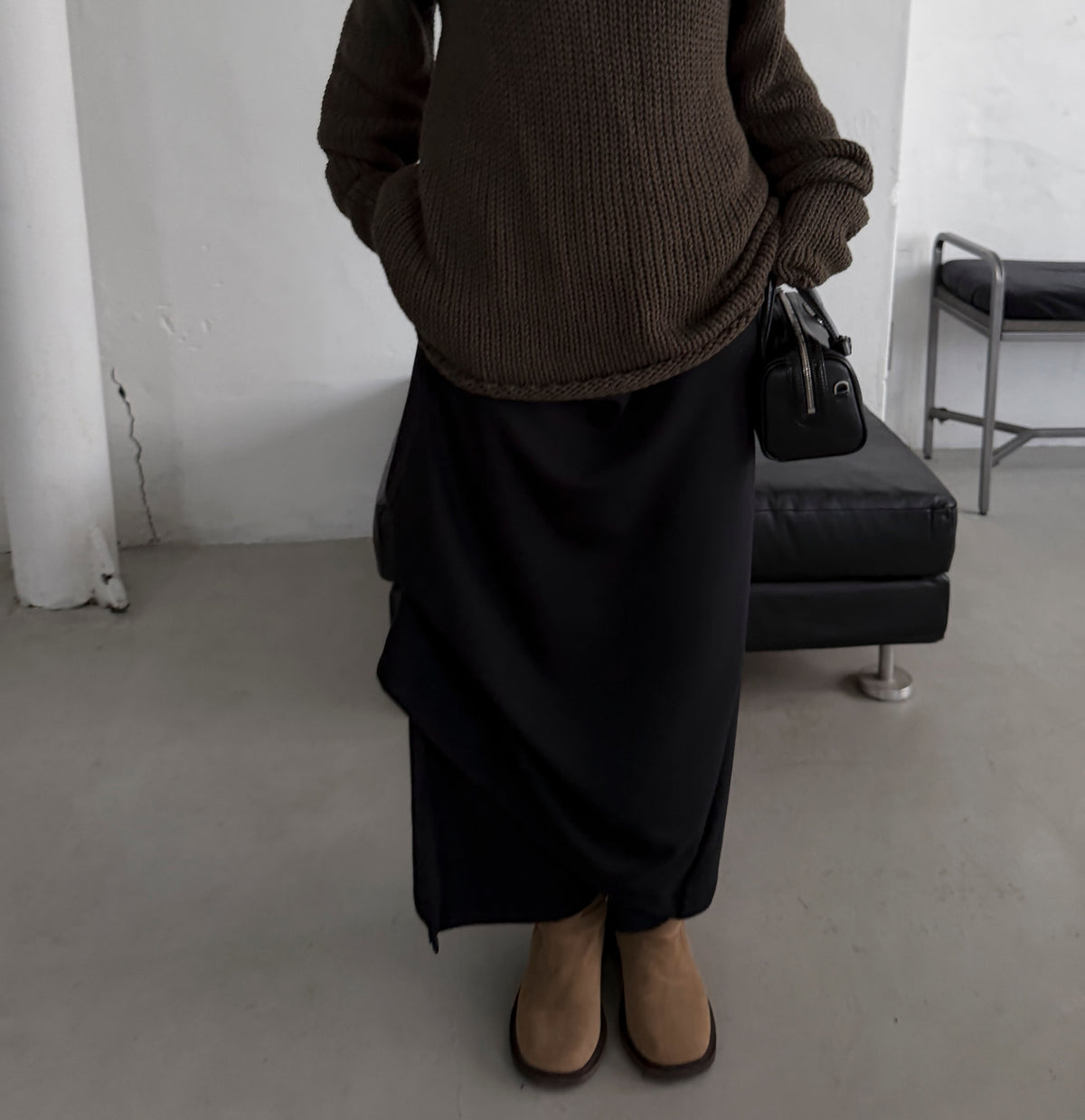 Front view of a charcoal maxi skirt styled with a black long sleeve top and black boots.