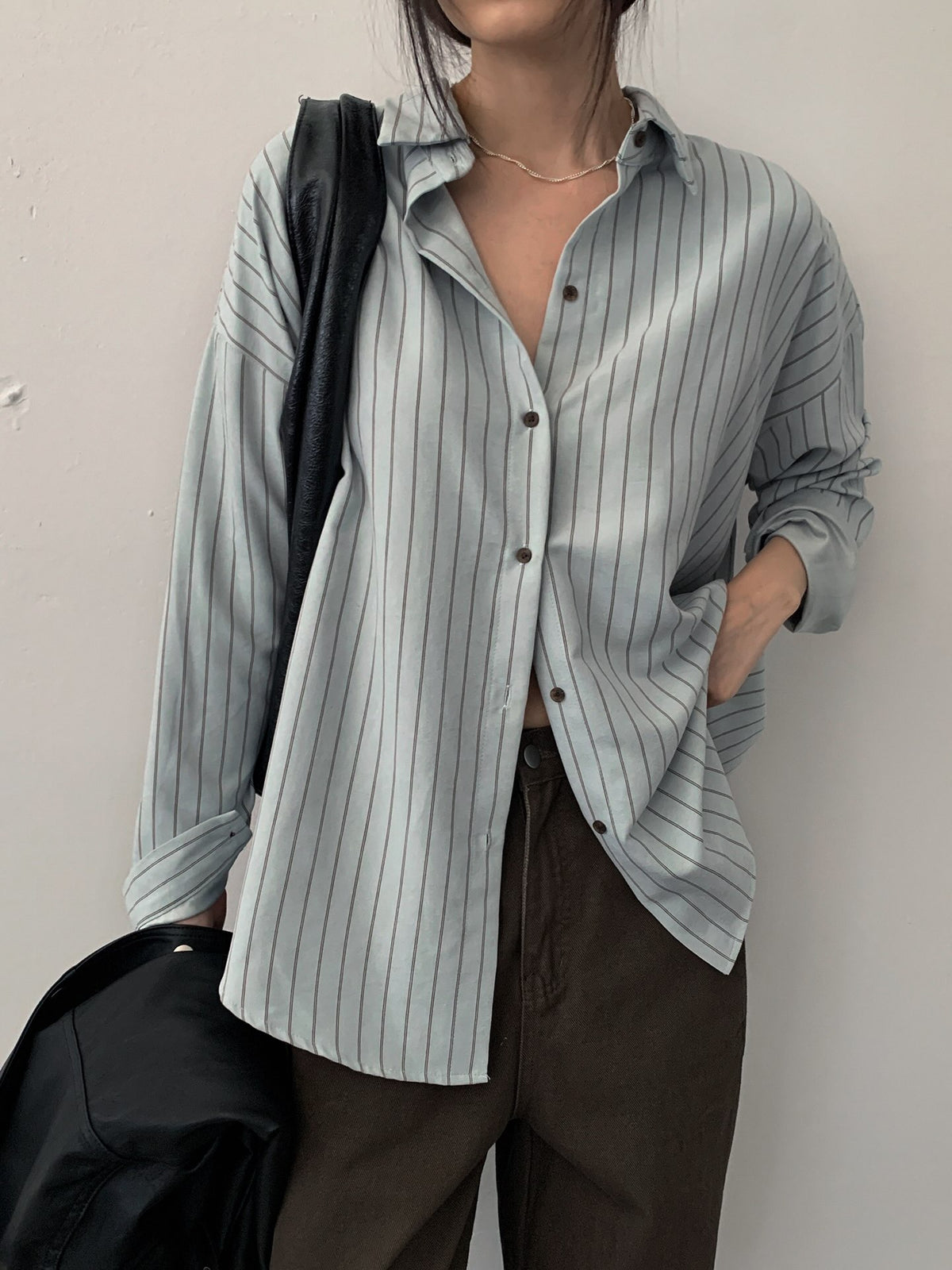 Close-up of a sky blue striped button-up shirt with long sleeves and buttoned cuffs.