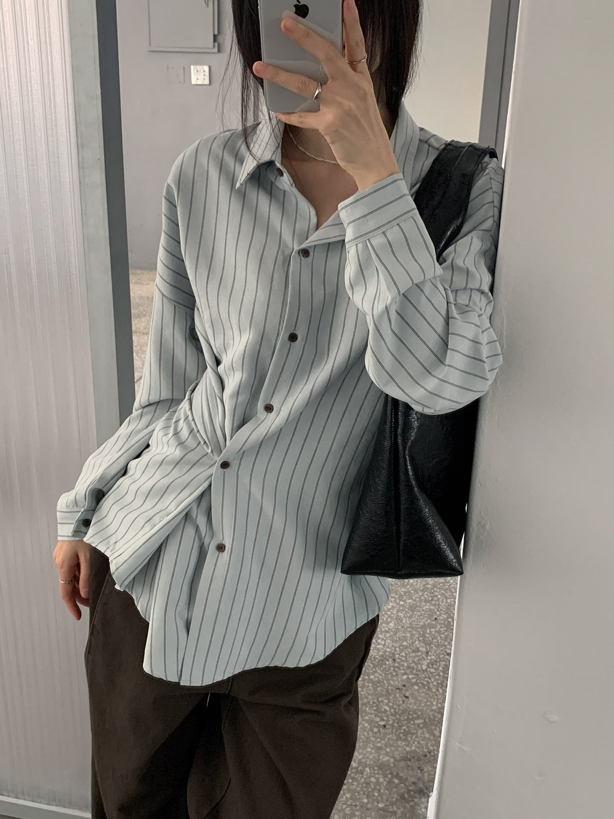 Woman wearing an ivory striped button-up shirt with a brown skirt.