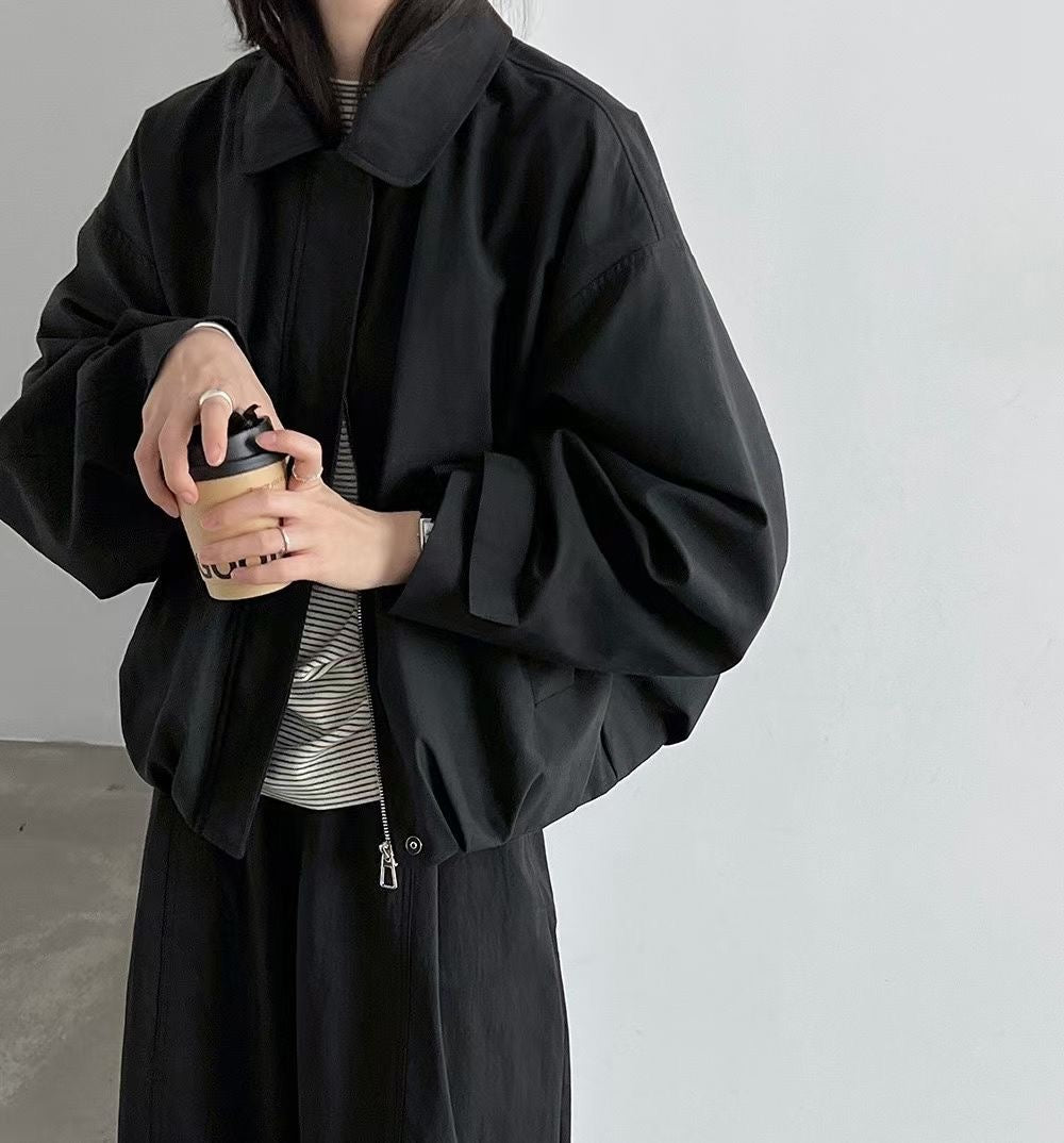 Close-up of a black jacket showing the zip front and buttoned cuff tabs.