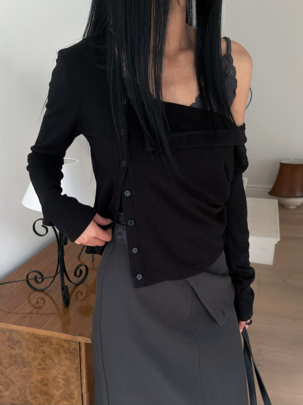 Ivory draped cardigan worn over a lace-trim top with black wide leg trousers.