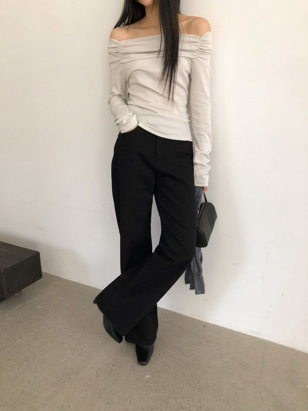 Mirror view of a charcoal ruched off-shoulder top with a white skirt and black tote bag.