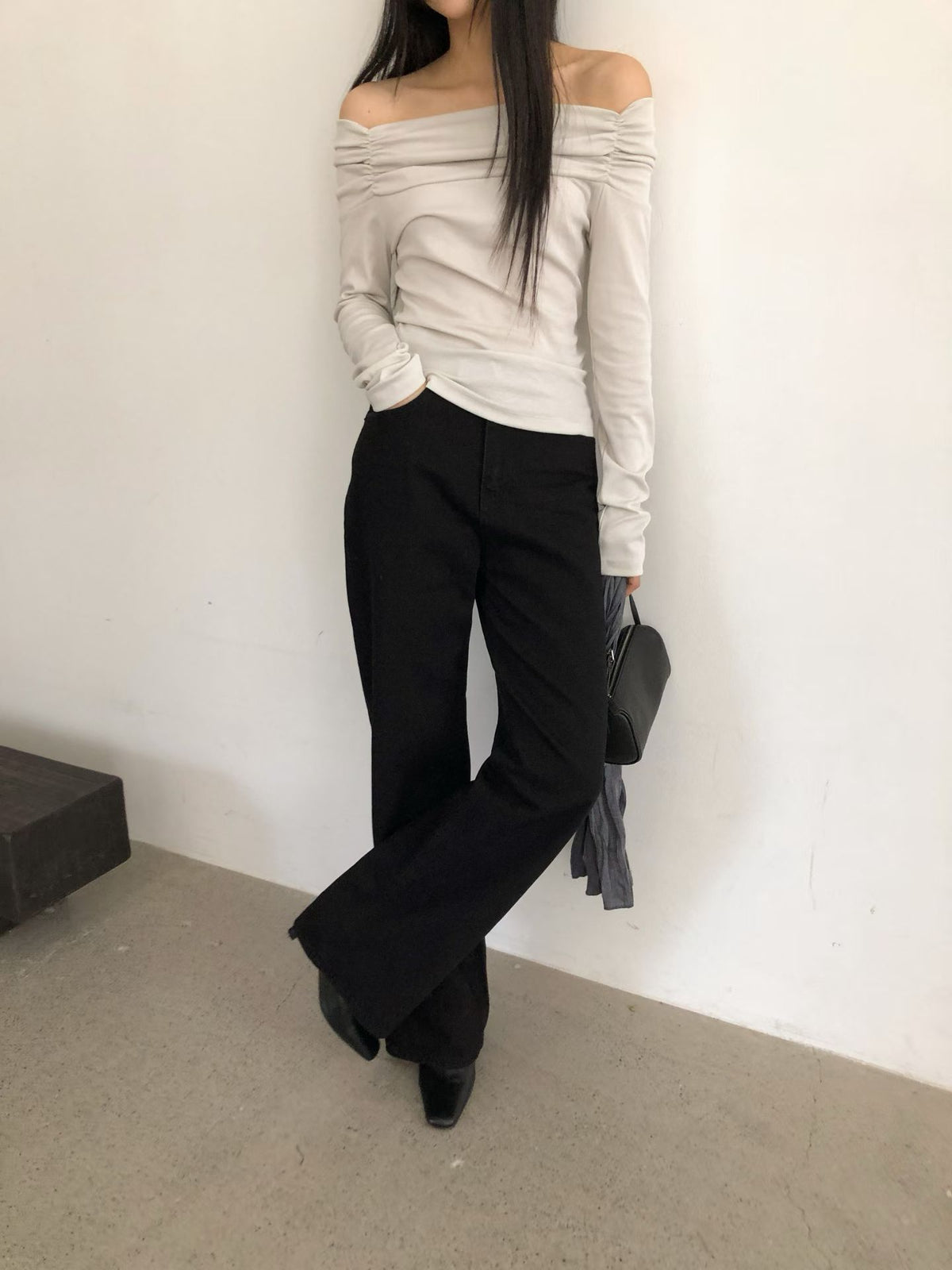 Mirror view of a charcoal ruched off-shoulder top with a white skirt and black tote bag.