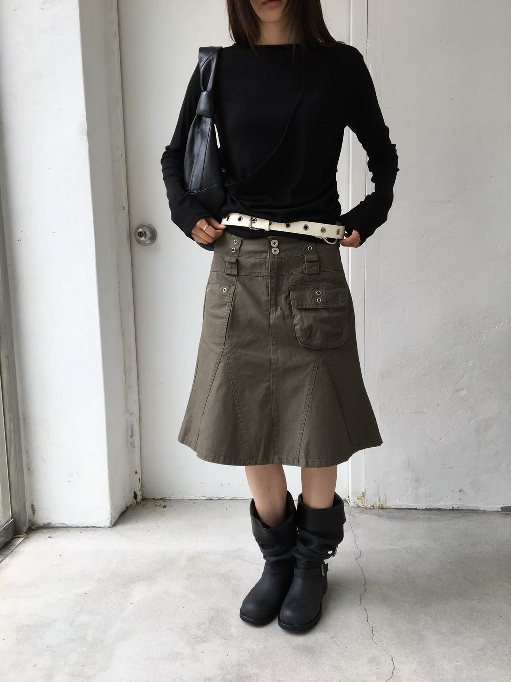 Khaki cargo skirt showing its front patch pockets and flared hem, worn with black boots.