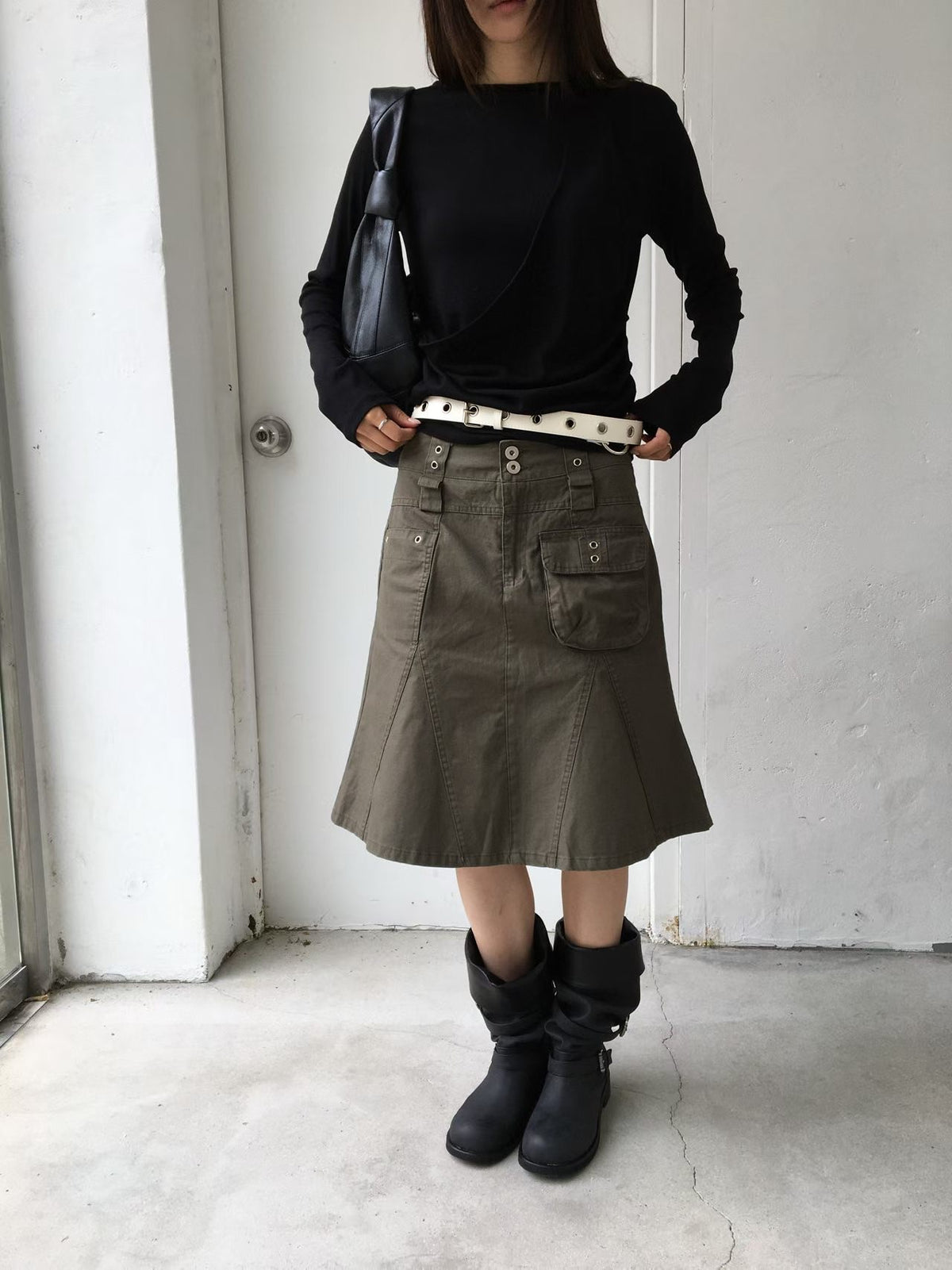 Khaki cargo skirt showing its front patch pockets and flared hem, worn with black boots.