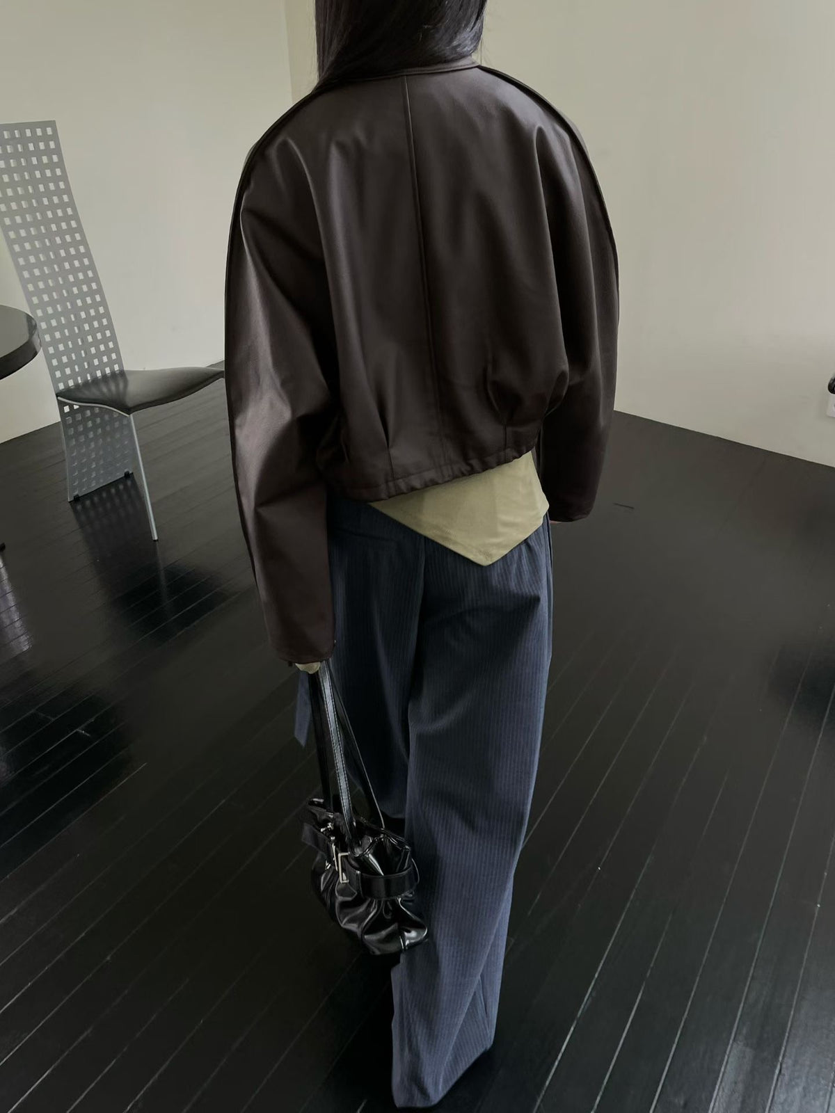 Back view of brown cropped faux leather jacket with centre seam and gathered hem