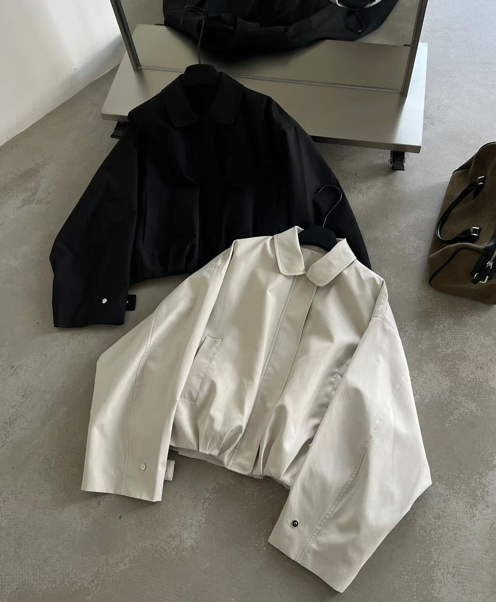Ivory collared blouson jacket worn partly open, showing its front zip and cuff tab.