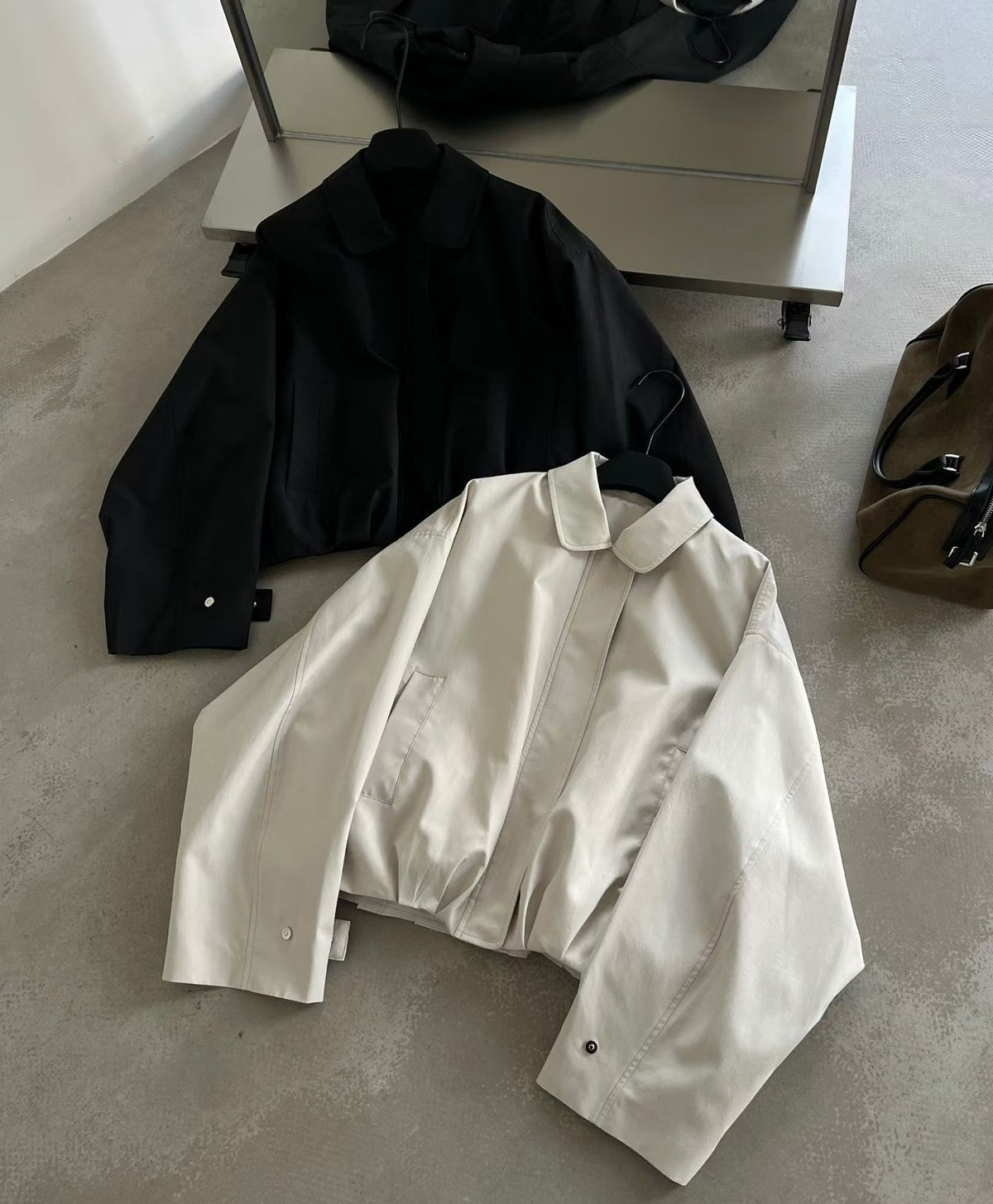 Ivory collared blouson jacket worn partly open, showing its front zip and cuff tab.
