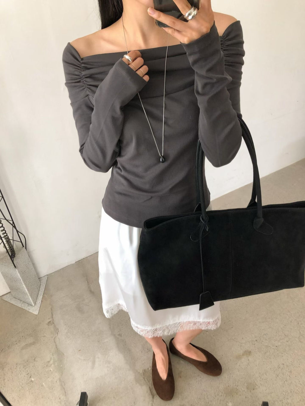 Front view of a grey beige top showing its off-shoulder neckline and gathered shoulders.
