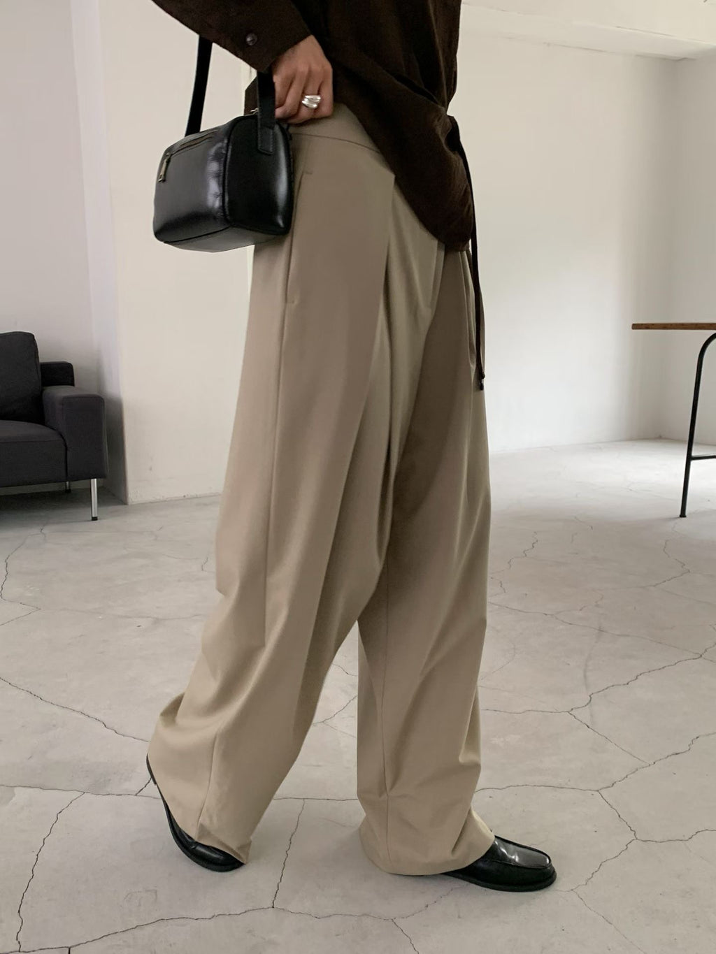 Back view of beige pants on a hanger showing belt loops and two welt pockets.