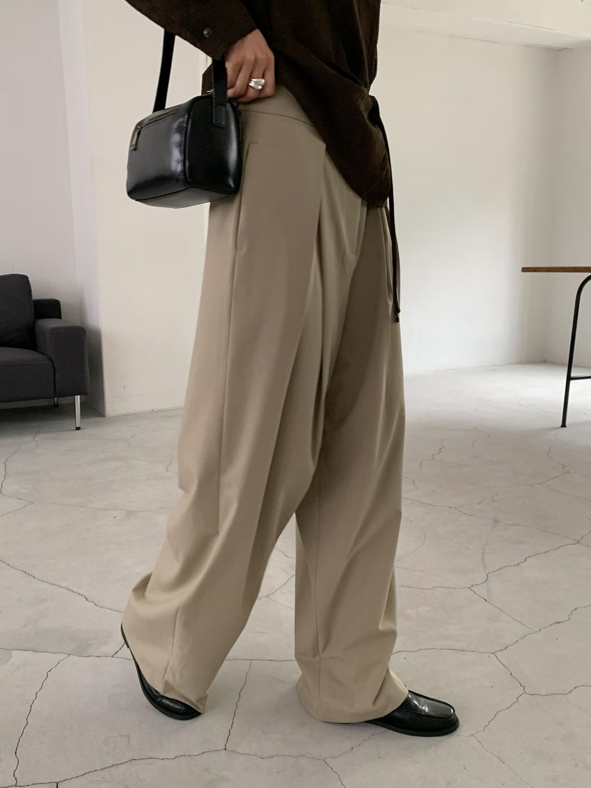 Back view of beige pants on a hanger showing belt loops and two welt pockets.