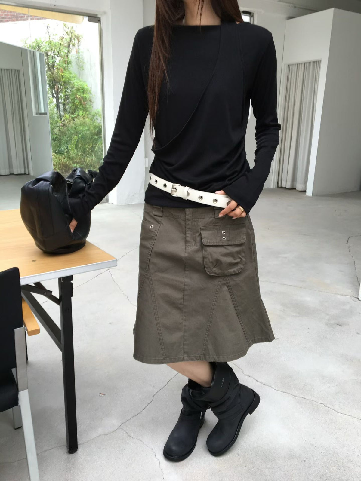 Angled view of a charcoal A-line cargo skirt showing a flap pocket and metal eyelet details.