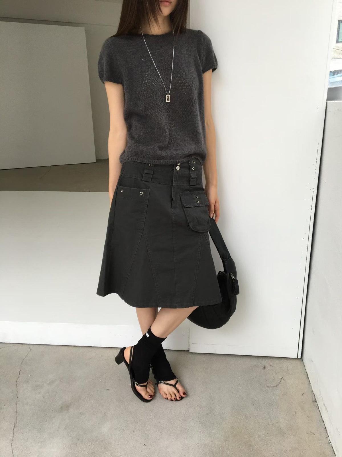 Side close-up of a charcoal cargo skirt showing the patch pocket, eyelets and panel seams.