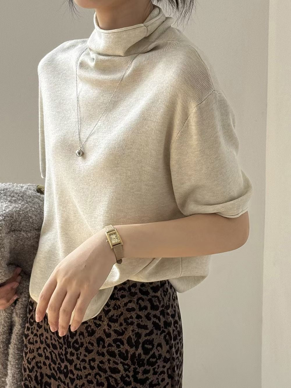 Close-up of the mock neckline and knit texture of an ivory sweater.