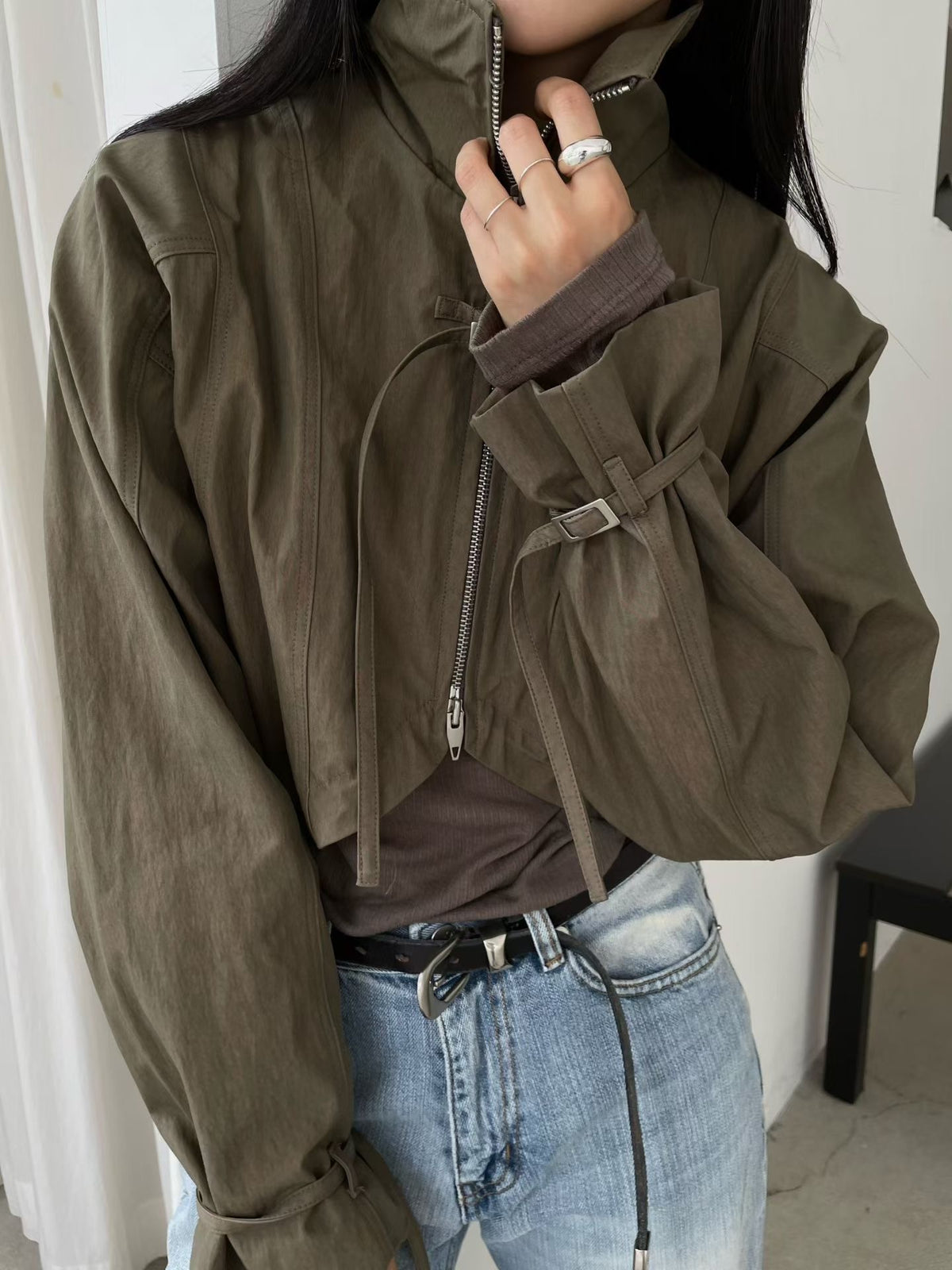 Khaki cropped bolero jacket, close-up of stand collar, zip and buckle cuff