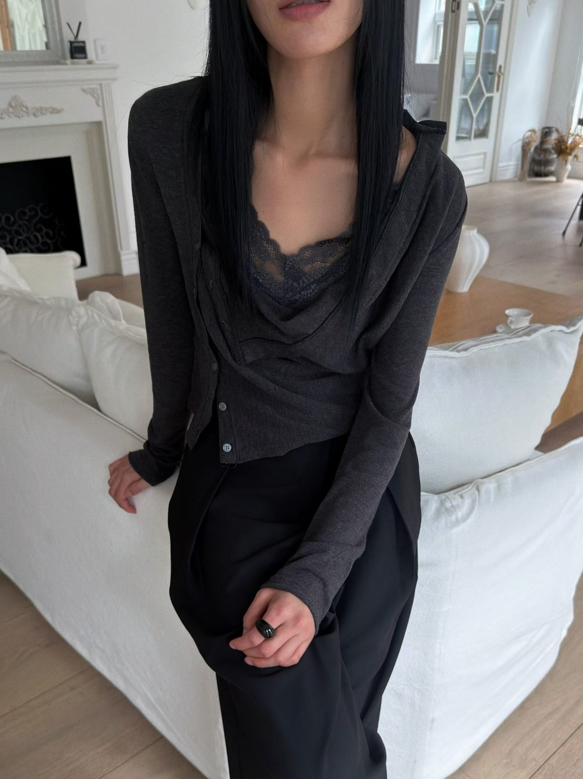 Close-up of a black cardigan showing its asymmetric buttons and draped front.