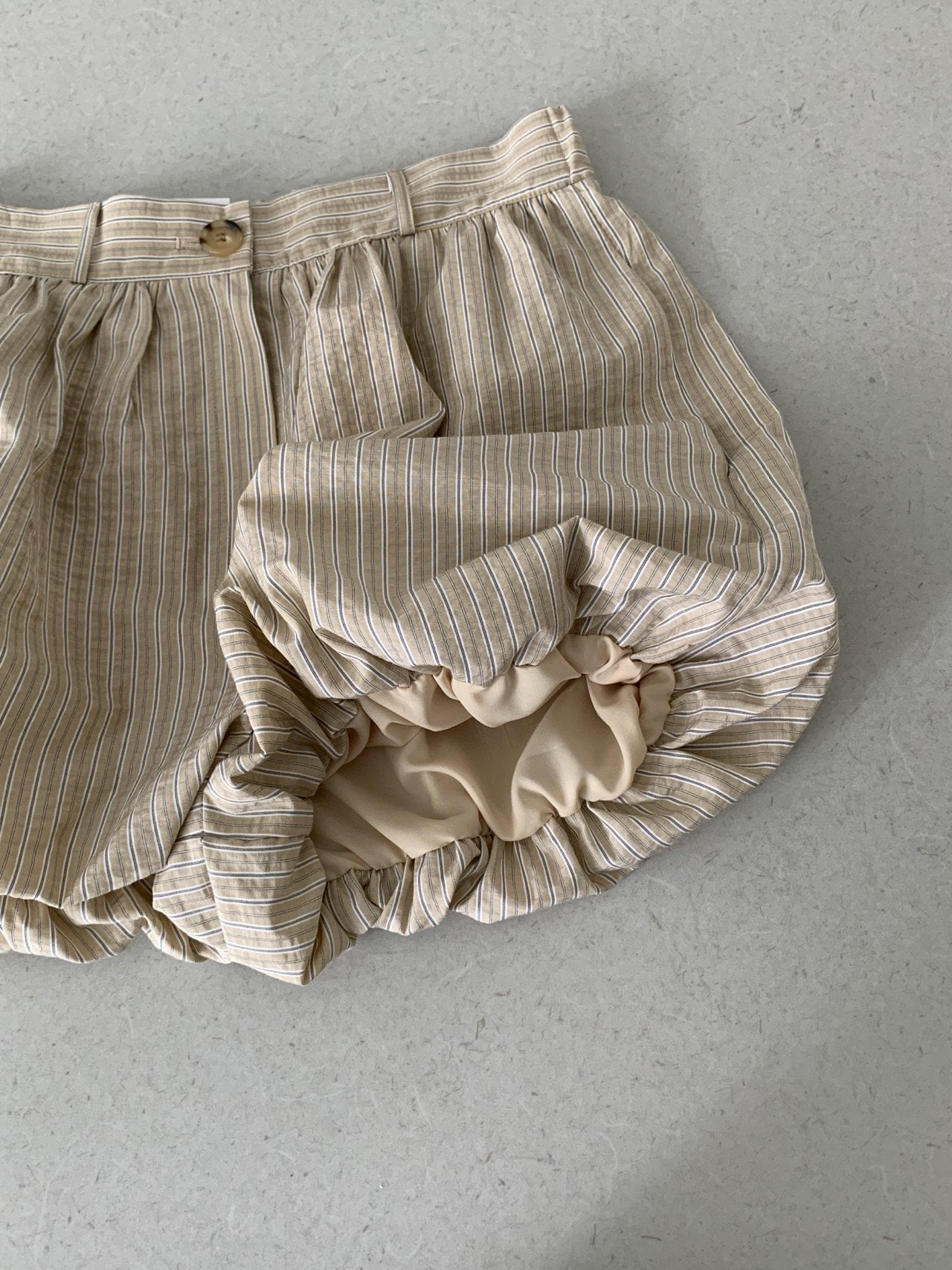 Vive L striped balloon shorts in Beige, flat lay detail showing elastic hem and button closure