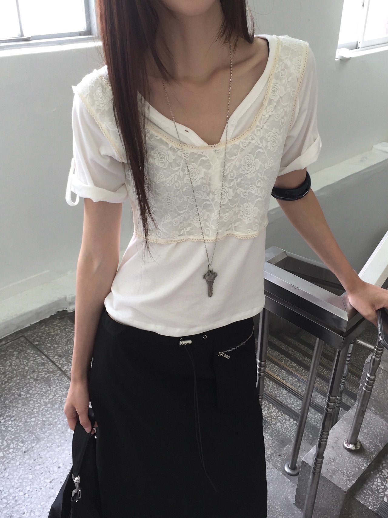 Nweol floral lace sheer bustier in Cream, styled on model front view layered over white short sleeve top with black maxi skirt standing by railing