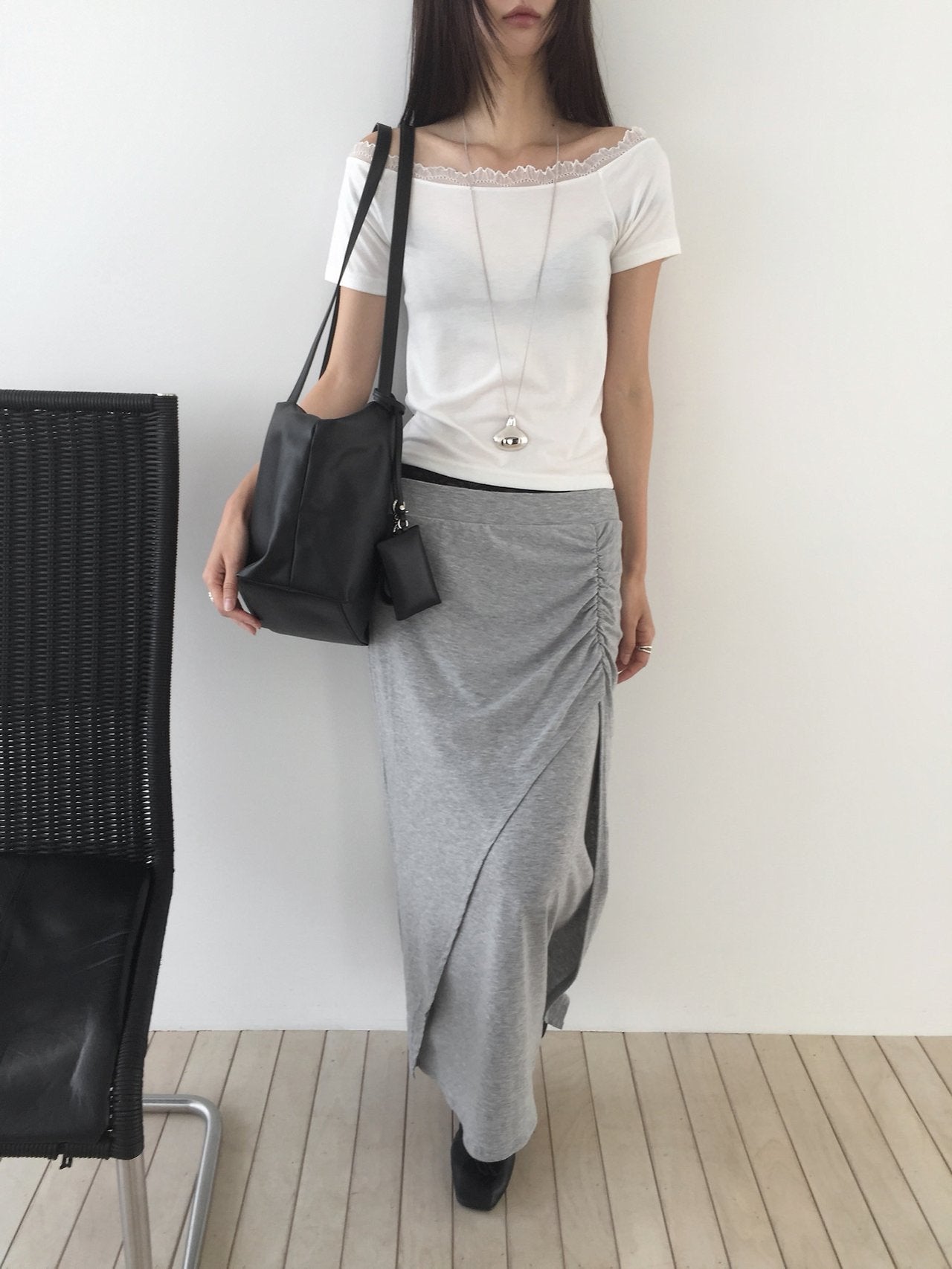 Nweol side ruched maxi skirt in Charcoal, styled on model front view with white tank top and black bag leaning on door