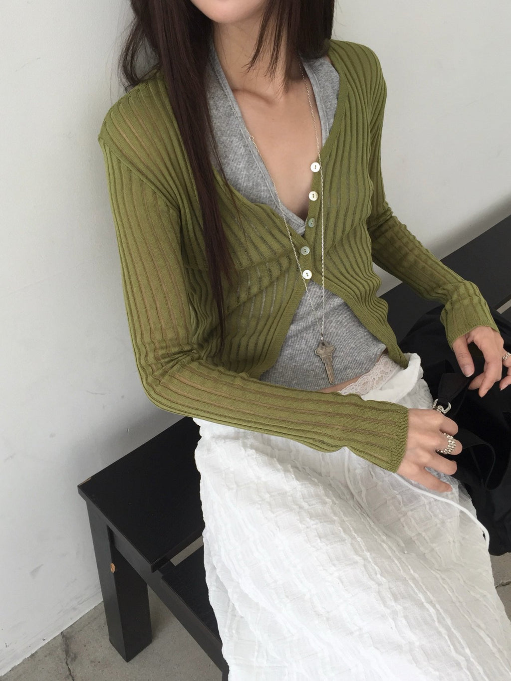 Nweol ribbed open knit crop cardigan in Olive, styled on model seated front view close-up button detail