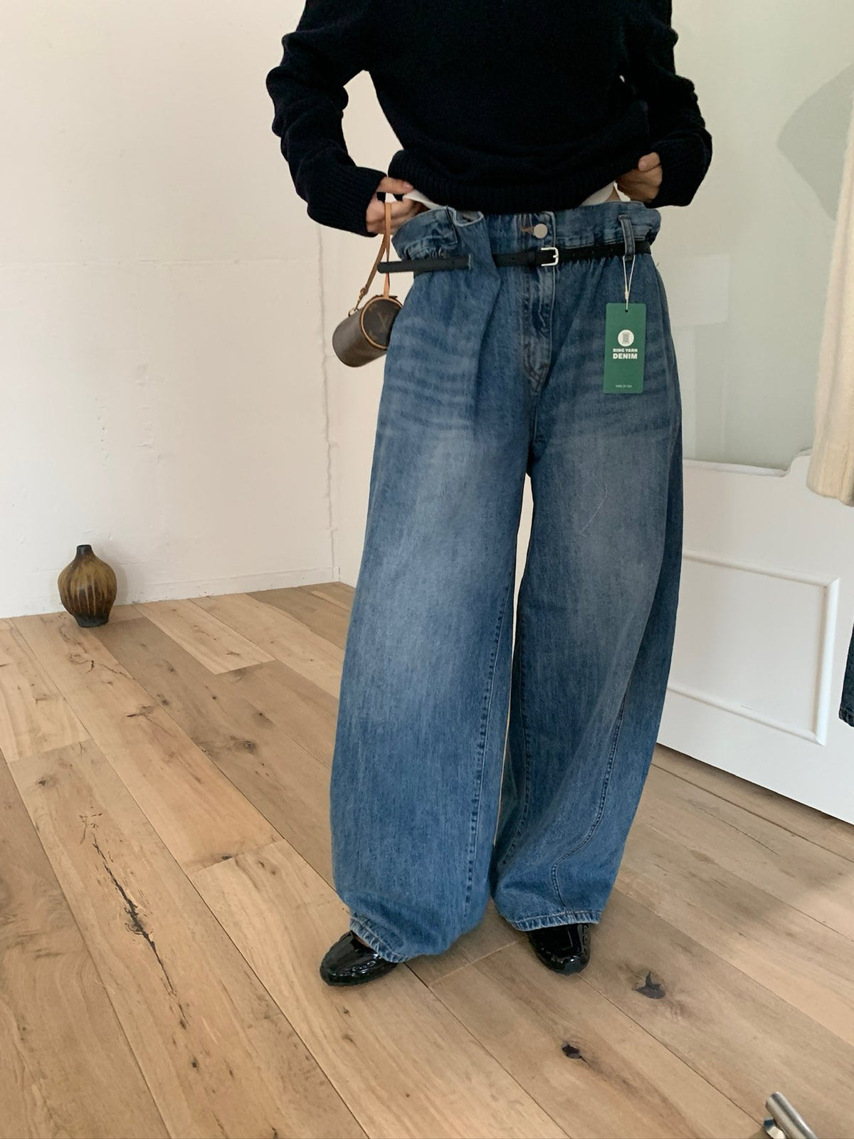 Blue wide-leg jeans worn with a black V-neck sweater
