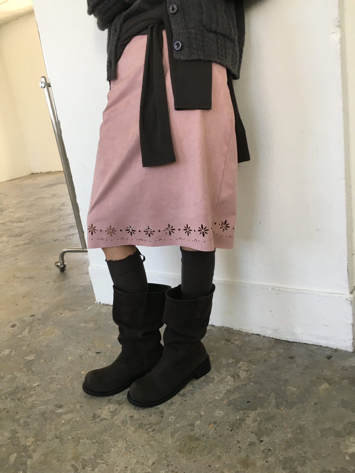 Side view of pink suede midi skirt with floral cutout hem