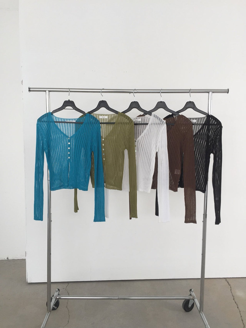 Nweol ribbed open knit crop cardigan in Blue, Olive, Ivory, Brown and Black, five colorways on rack