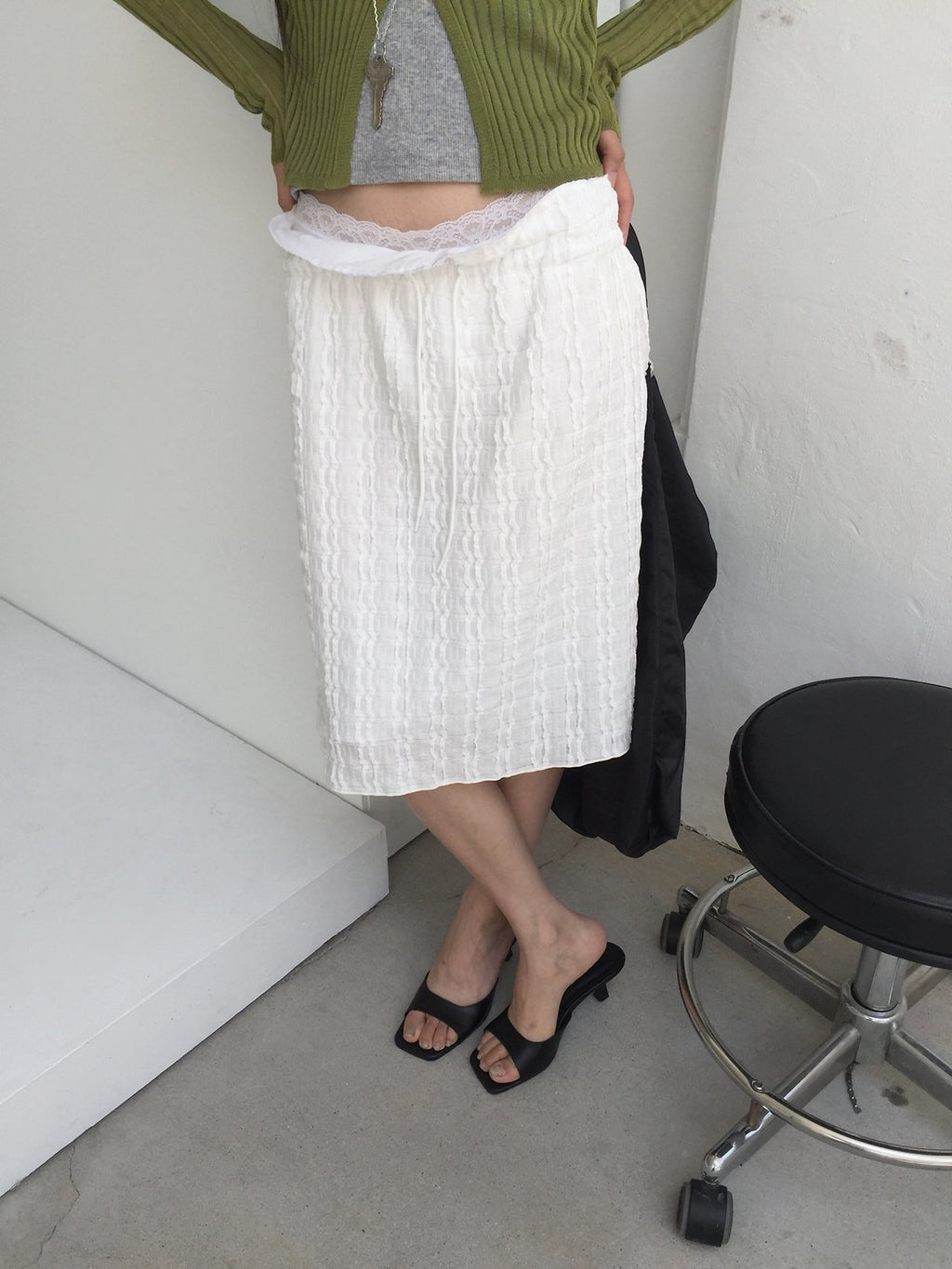 Nweol bubble texture midi skirt in Ivory, styled on model front view leaning on shelf with olive cardigan