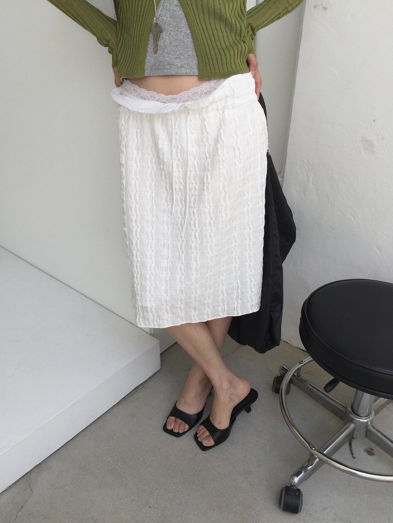 Nweol bubble texture midi skirt in Ivory, styled on model front view leaning on shelf with olive cardigan
