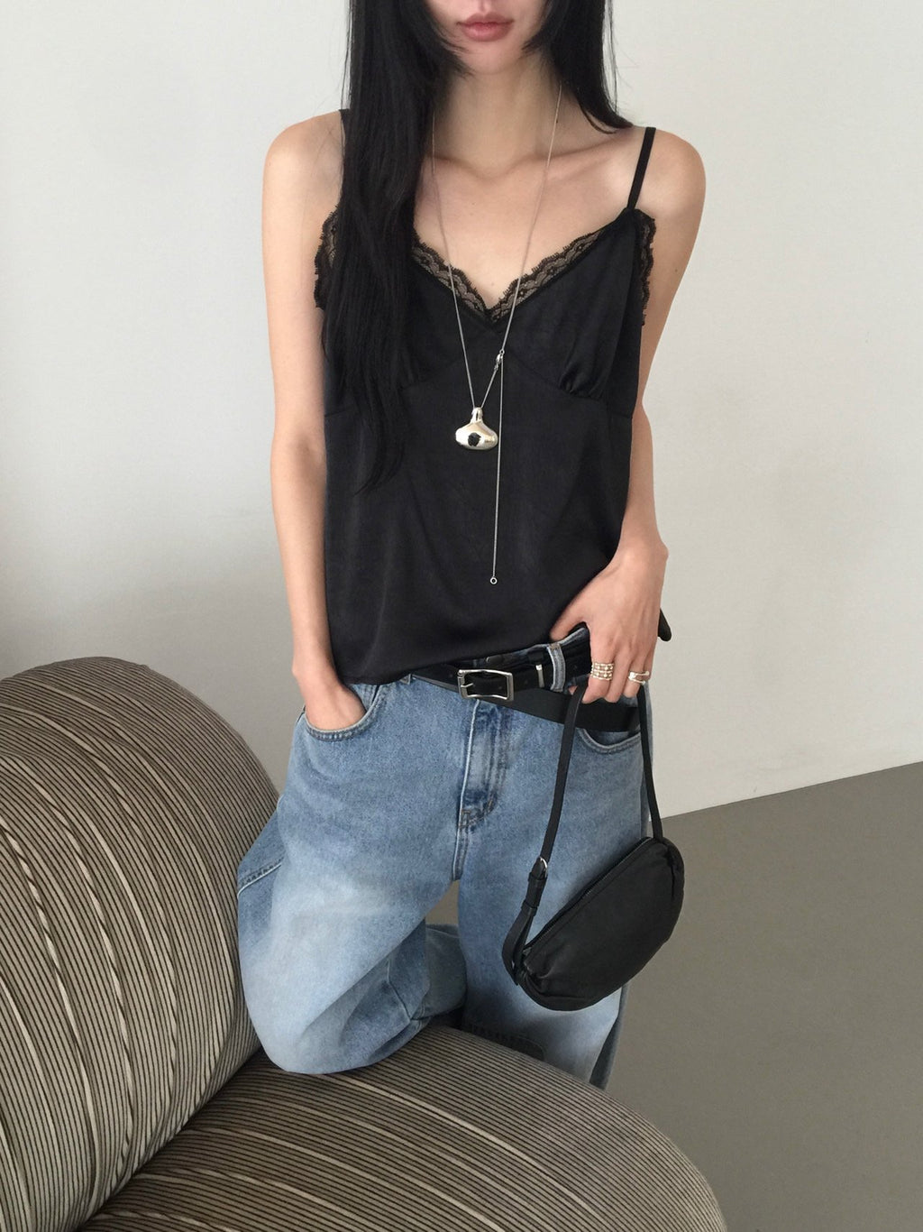 Nweol lace trim satin tank top in Black, styled on model back view with light blue wide leg jeans