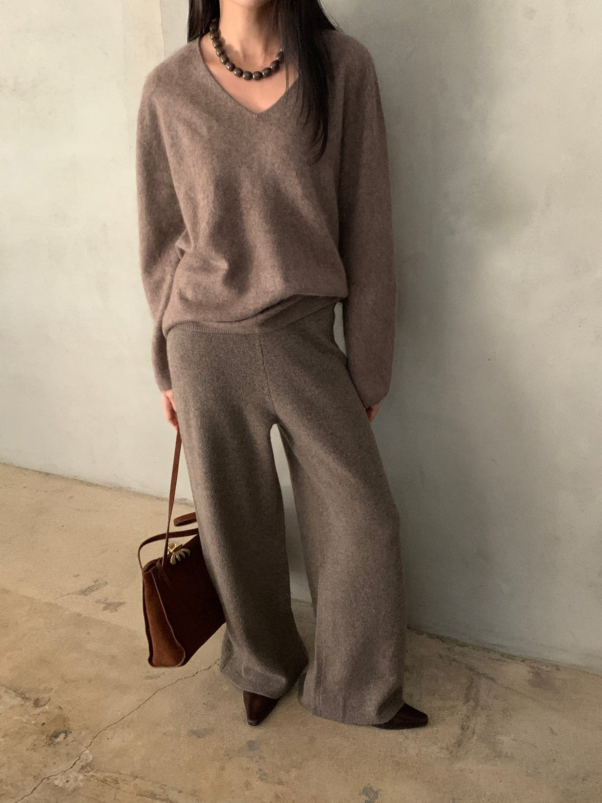 Side view of charcoal wide-leg knit pants worn with a grey top