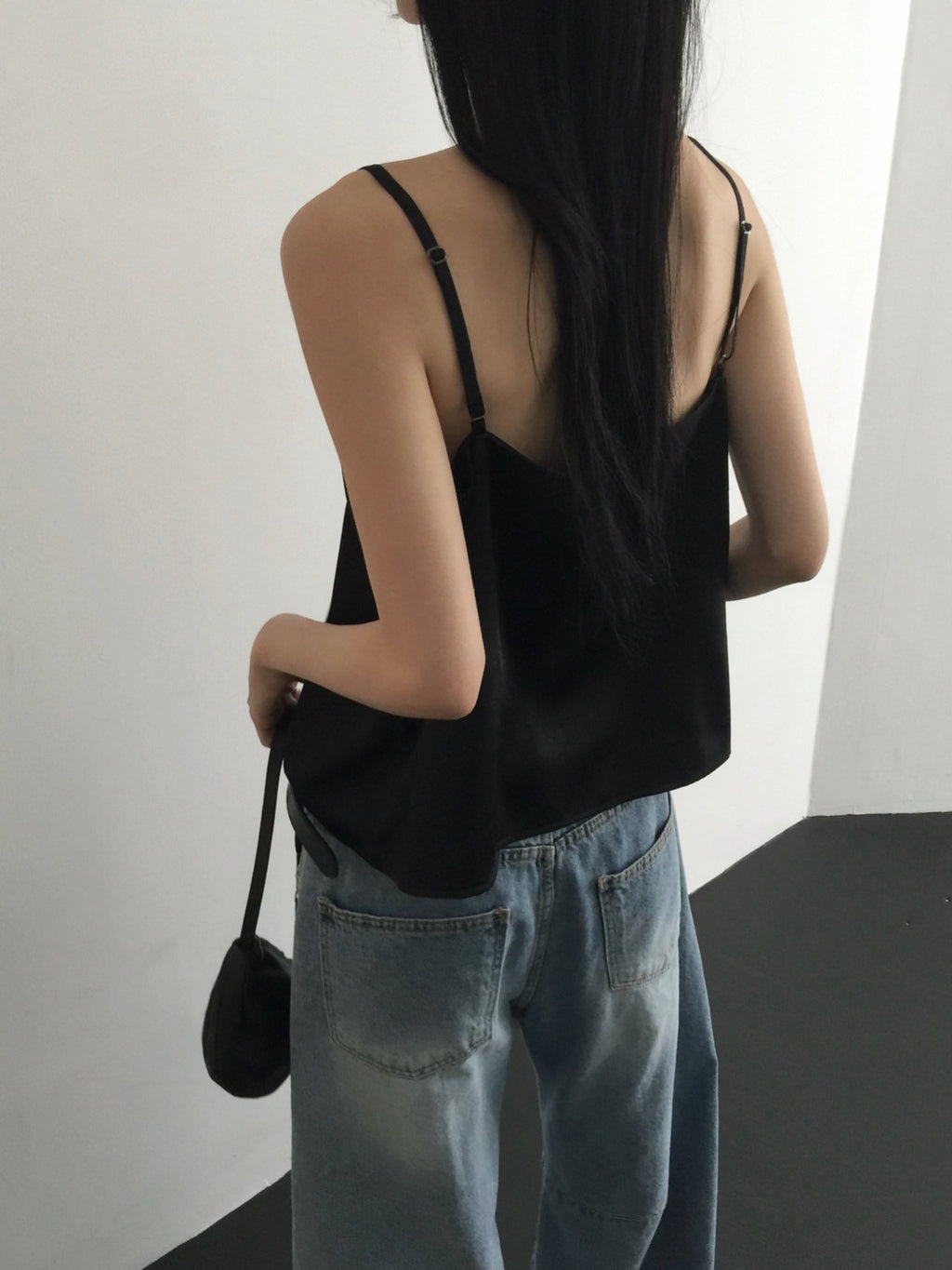 Nweol lace trim satin tank top in Black, styled on model front view with light blue wide leg jeans