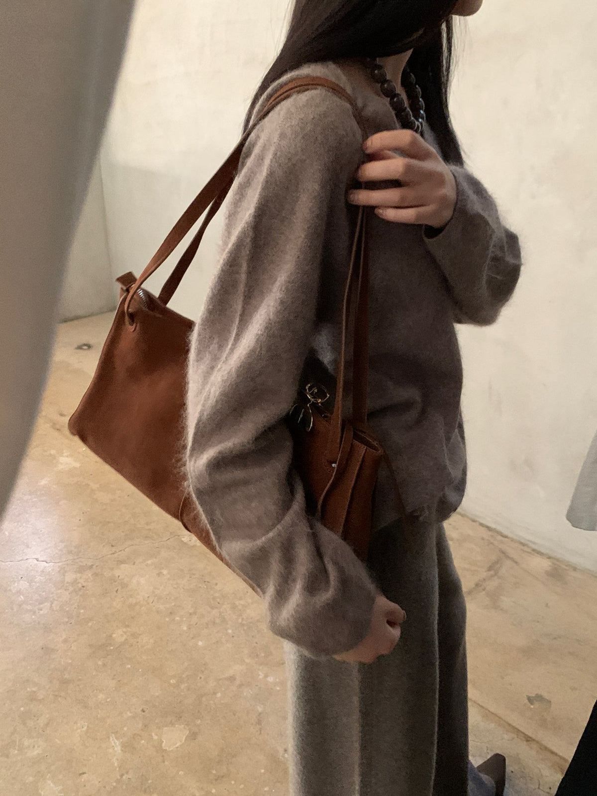Brown knit sweater styled with a patterned scarf and jeans