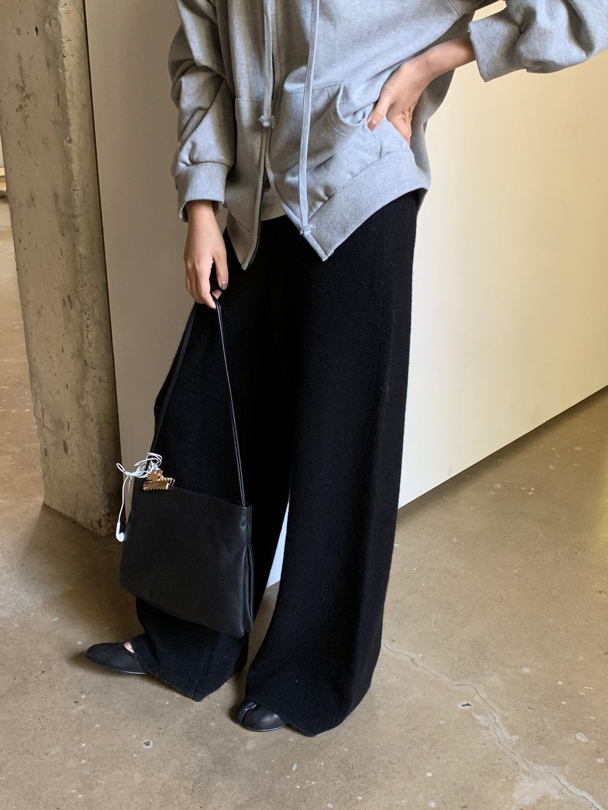 Front view of black wide-leg knit pants worn with a grey zip hoodie