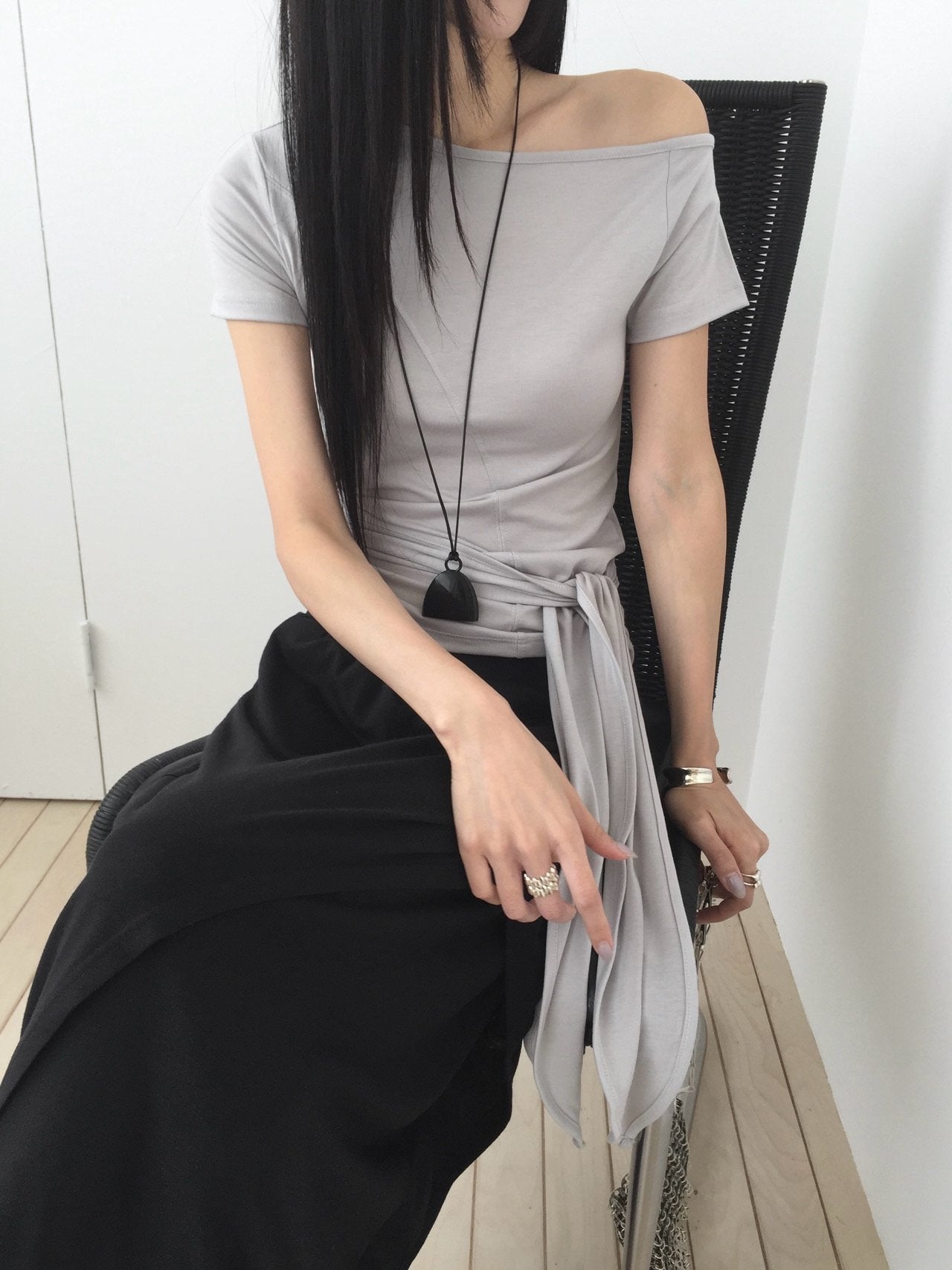 Nweol off-shoulder crop top with tie waist in Light Grey, styled on model front view with black maxi skirt full length