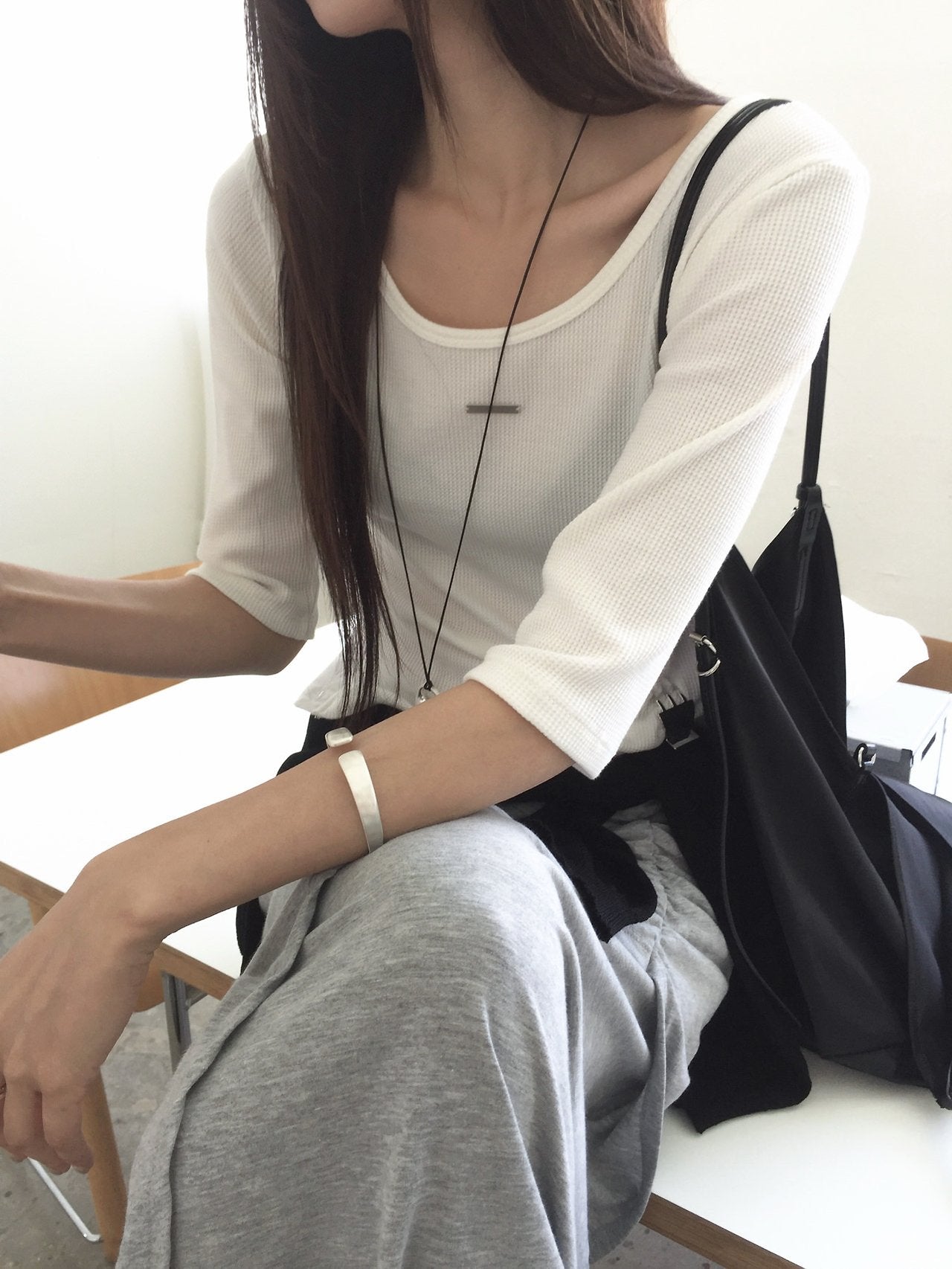 Nweol waffle knit crop half sleeve top in Ivory, styled on model front view close-up metal logo plate detail